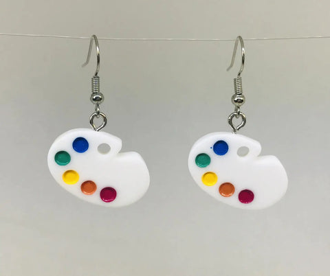 Novelty dangle earrings in the shape of two small white artist’s palettes filled with colorful paints. On metal fishhook hardware 