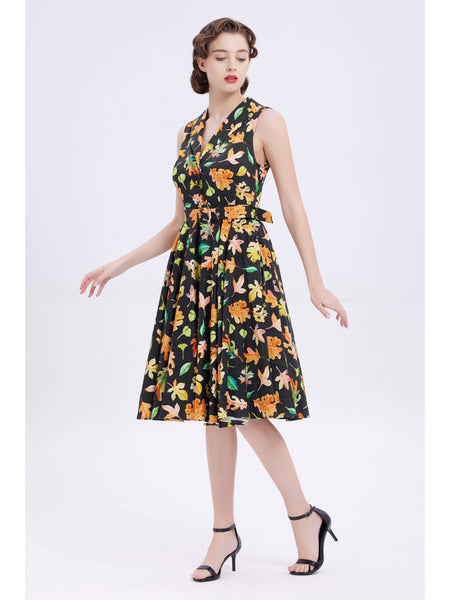 "Autumn Leaves" dark green (almost black) background with allover leaves in oranges and greens print dress sleeveless shirtwaist fitted shawl collar button-front bodice, removable self belt with buckle, flared just below the knee length skirt, shown on model