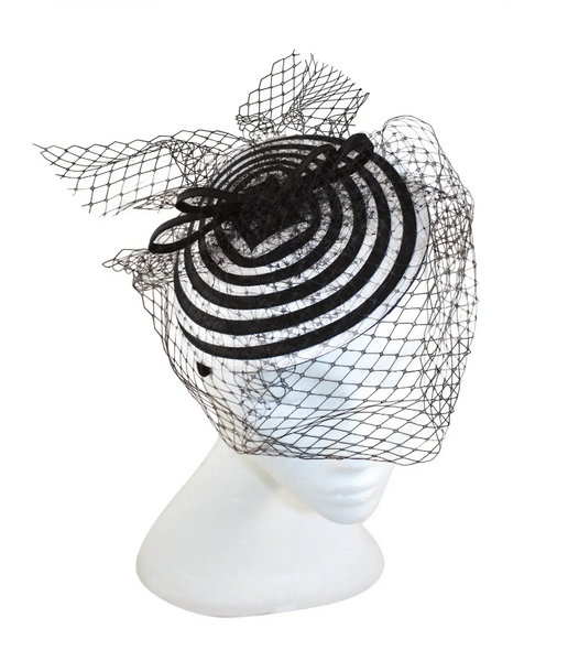 black and white spiral swirl fascinator with black bow and netting on a satin covered headband, shown on mannequin head