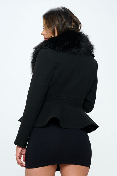 A black faux wool jacket with oversized black faux fur collar and peplum waist. It has a button closure in the middle of the waist. Shown on model from behind to show back of coat and peplum 