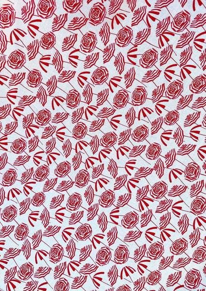 creamy white cotton with allover print of rich red stripe-y beach umbrellas fabric swatch close up