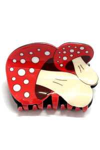 A plastic claw style hair clip in the shape of two red and white toadstool mushrooms 