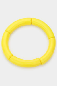 A bright yellow and chartreuse bangle made of segments of resin strung on elastic cord