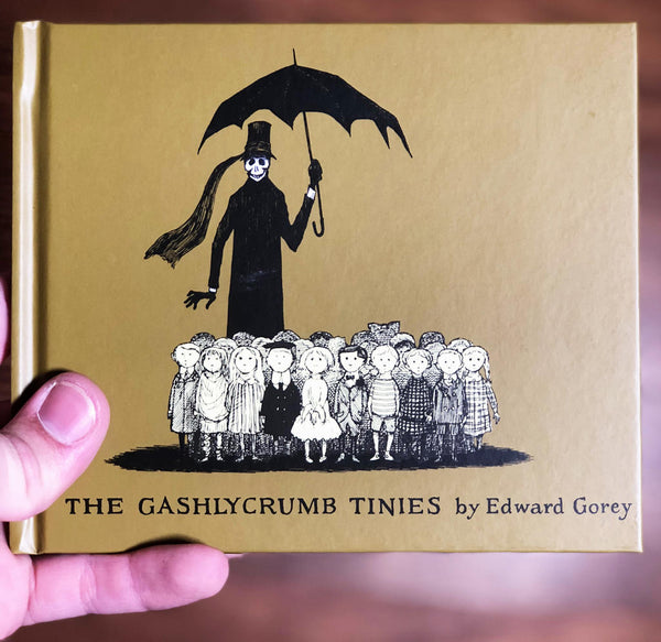 The cover for the 1963 Edward Gorey book The Gashlycrumb Tinies. Being held to show size and scale