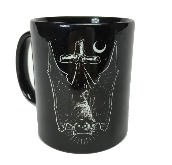 The other side of the black ceramic mug with a white illustration of an upside down bat with its eyes open