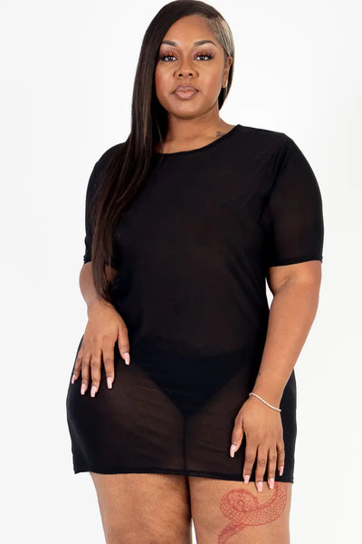 A plus size model wearing a short sleeved black mesh mini dress.