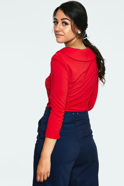 bright red stretch knit top with collared v-neckline with covered button detail, 3/4 length sleeves, fitted silhouette, and hip length. shown back view on model.