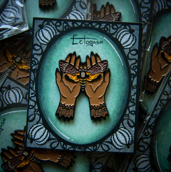 yellow, and brown Death's Head Moth gently held in witchy hands enameled metal double clutch back fastener pin, shown on illustrated backer card packaging