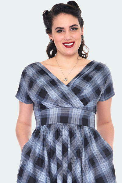A close up shot of the model wearing the plaid dress to better show the cinched waistline and gathered fabric at the bust