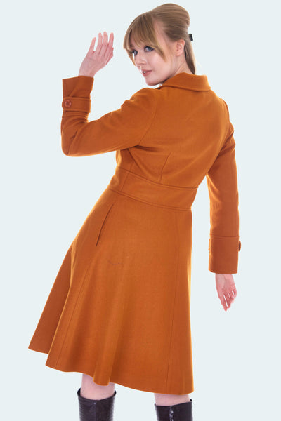 Burnt orange wool double breasted coat with fit and flare silhouette and pockets. Hits at knee. Shown on model from behind 
