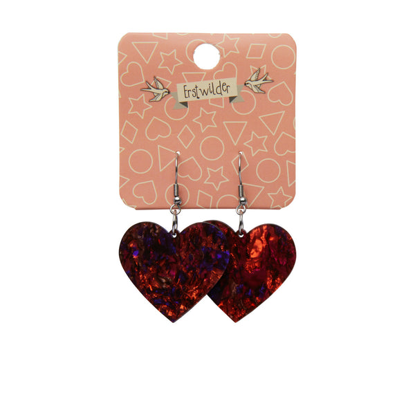pair heart shaped dangle earrings in shiny red, purple, black, and caramel Lava texture 100% Acrylic resin, shown on illustrated hang tag packaging