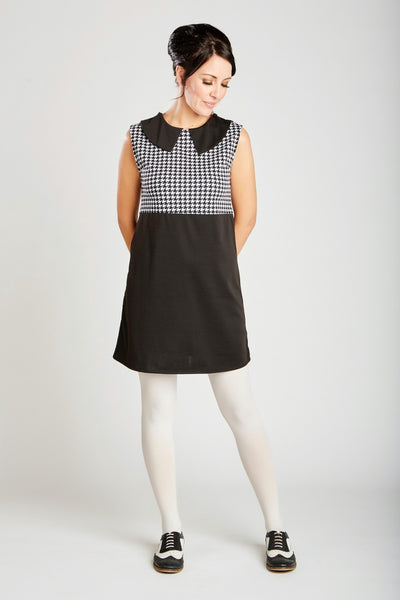 60s inspired a-line stretch knit shift dress features a black & white houndstooth empire waist bodice with solid black pointed collar and body in a mid-thigh mini length, shown on model