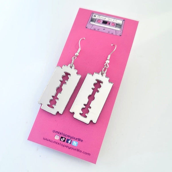 Small silver mirrored laser cut acrylic razor blade shaped dangle earrings. Shown on packaging card