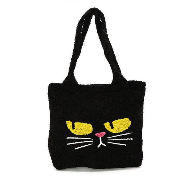 black teddy/sherpa fuzzy fabric tote bag with embroidery details of grumpy looking yellow eyes, pink nose, and white whiskers. Bag has matching fuzzy shoulder straps. Shown from front