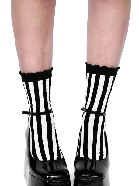 Pair of off-white crew socks with black ruffle cuff, black and white horizontal stripe, and black toes and heels; Shown worn by model wearing platform heels