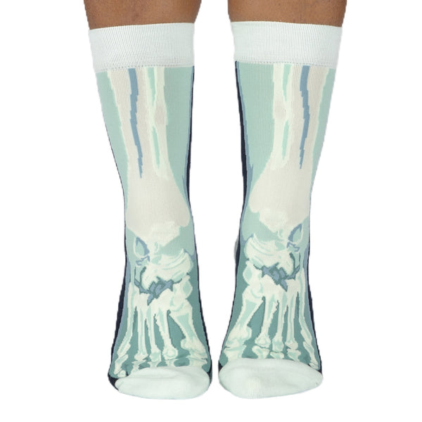 A pair of unisex cotton blend crew socks with a light blue and white x-ray style skeleton foot design, shown on a person's feet from the front against a plain white background.