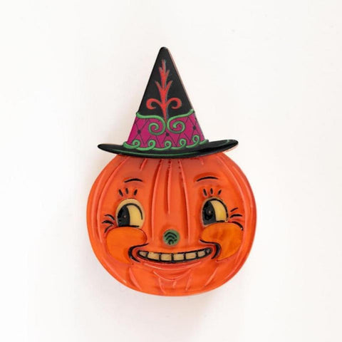 layered acrylic resin brooch in the shape of an orange jack-'o-lantern with black details and green nose wearing a black witch hat with red, fuchsia and green detail