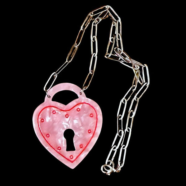 16" silver metal paperclip style chain with pendant in pearly pink marbled acrylic in the shape of a heart-shaped padlock with painted red detail. Shown on black background