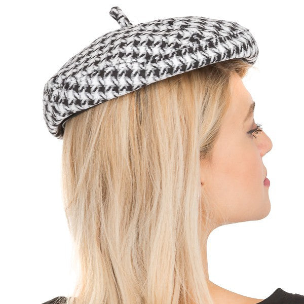 Person wearing a black and white houndstooth pattern beret on a white background