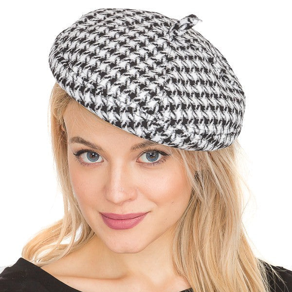 Woman wearing a black and white houndstooth patterned beret on a white background