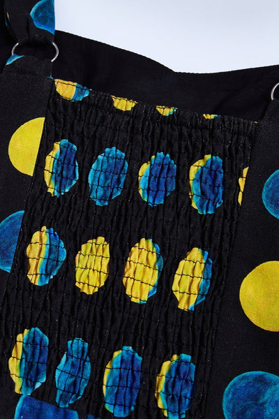 sleeveless black background yellow and blue moon phase print dress with a fitted sweetheart neckline princess seamed bodice with adjustable straps, removable self sash belt, swingy gathered full circle just below the knee length skirt. Shown flat in close up of shirring at back of bodice