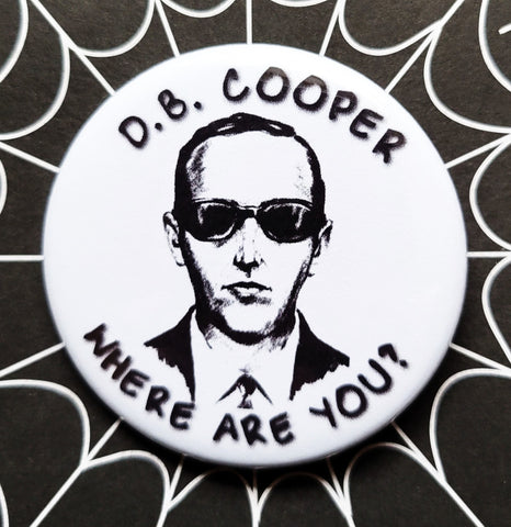 1.25” round pinback button with portrait of D.B. Cooper and message “D.B. COOPER WHERE ARE YOU?” on white background 