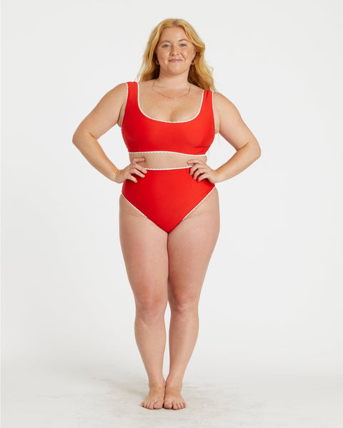 model wearing red and white gingham print reversible bikini. Top has scoop neckline and white rickrack style trim. Shown from front with solid red side worn