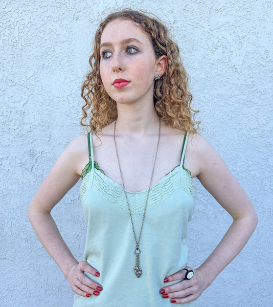 silver metal link chain toggle necklace with trio of heart charms hanging from three smaller chains at front of necklace. Worn by a model with chain in single layer for longer necklace