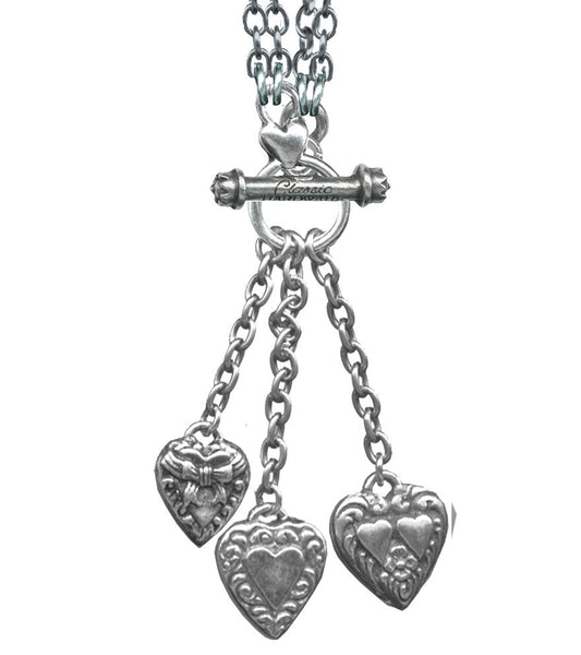 silver metal link chain toggle necklace with trio of heart charms hanging from three smaller chains at front of necklace. Charms shown in close up