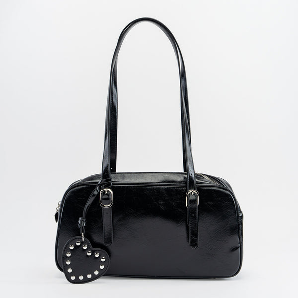 shiny black textured faux leather bowler bag with adjustable shoulder straps, sturdy silver metal zip closure, and studded matching faux leather heart-shaped mirror bag charm. Shown from front