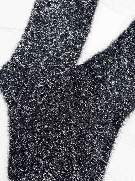 a pair of fuzzy knit crew length socks in black with long strands of silver lurex woven in and sticking out. Shown flat on white background in close up