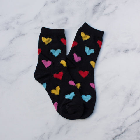 black knit socks with red, blue, yellow, pink knit-in pattern of hearts with stitch effect. Shown flat