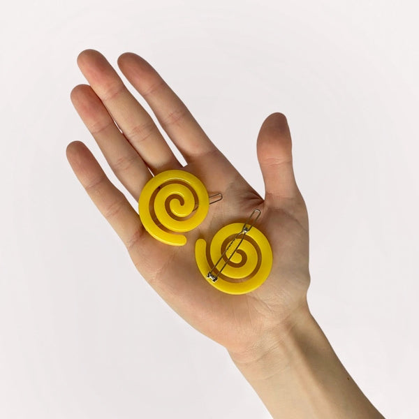 bright yellow acetate ball-and-clasp barrette in a rounded spiral shape. Shown held for scale