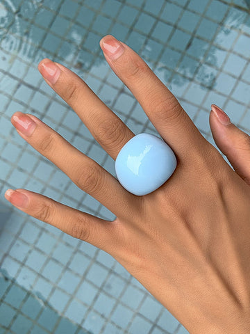 Rounded acrylic cocktail ring in light blue. Worn by a model