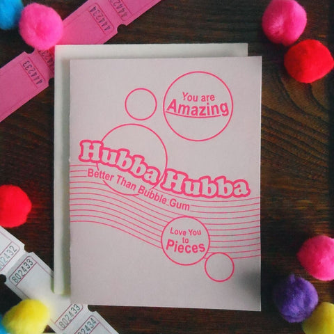 Pale pink cardstock letterpress note card with “Hubba Hubba” “You are amazing” “Better than bubble gum” “Love you to pieces” written in bright pink font meant to resemble Hubba Bubba gum packaging 