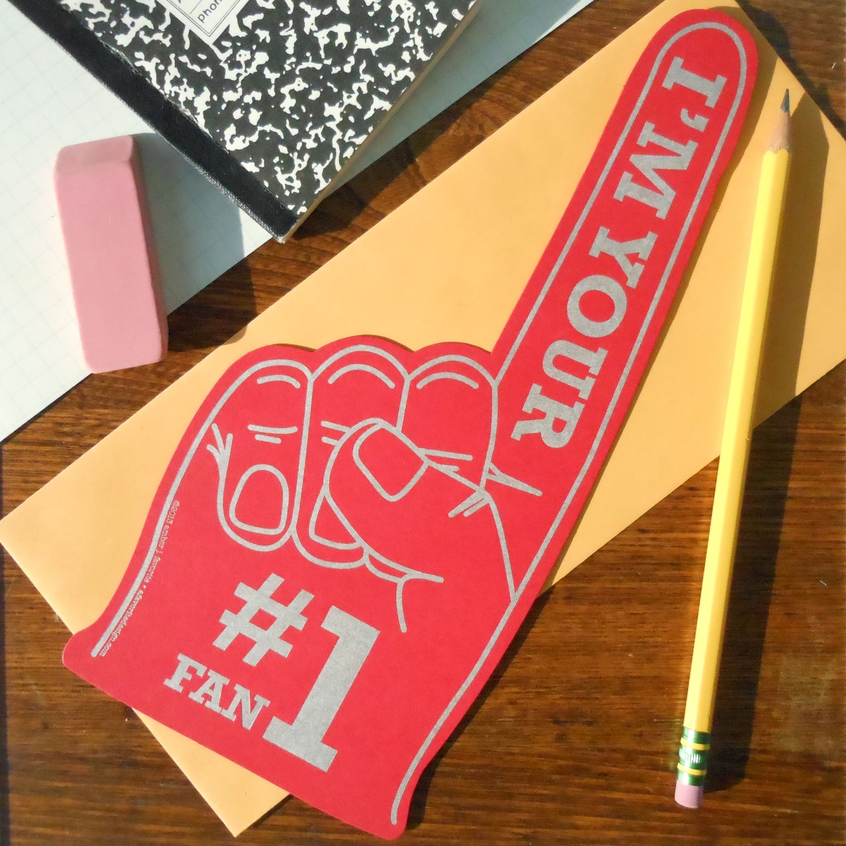Die cut red greeting card in the shape of a novelty foam finger, with “I’m Your #1 Fan” written in grey