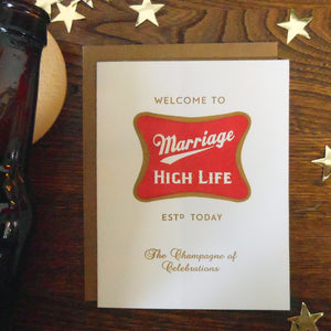 Letterpress greeting card with “Welcome to Marriage High Life EST. Today” “The Champagne of Celebrations” designed to resemble Miller High Life beer packaging 