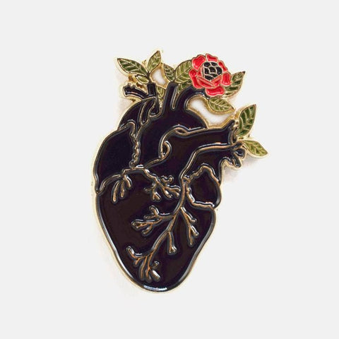 gold metal enamel pin of a black heart with red and green flower growing out of a ventricle. Shown flat