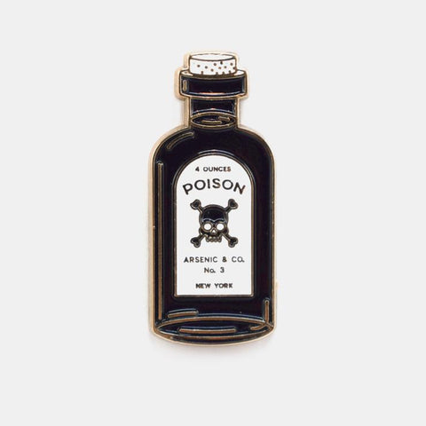 Gold metal enamel pin of a bottle with cork and label “4 OUNCES POISON ARSENIC & CO. NO.3 NEW YORK” written around a black skull & crossbones. Shown from front