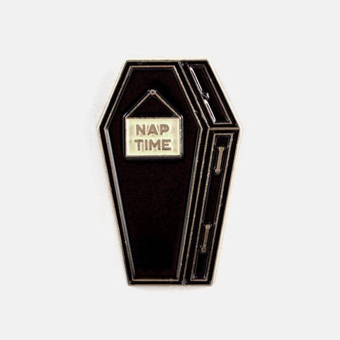 gold metal enamel pin of a black coffin with sign nailed to front reading "NAP TIME". Shown from front