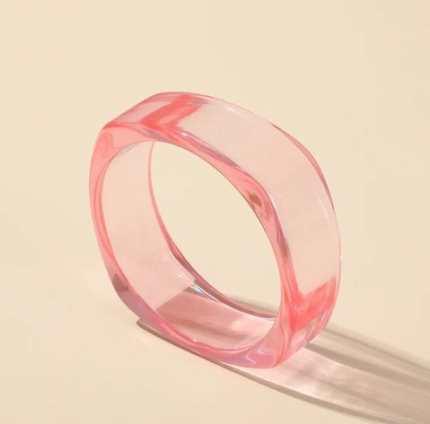 A cotton candy pink lucite bangle with a rounded square shape shown on its side