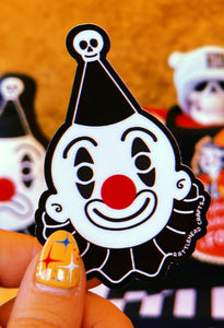 black and white smiling clown die-cut vinyl sticker shown held in front of an orange background