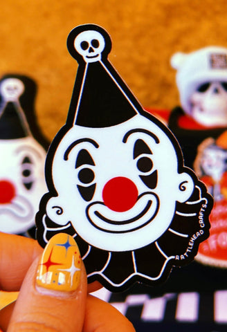 black and white smiling clown die-cut vinyl sticker shown held in front of an orange background