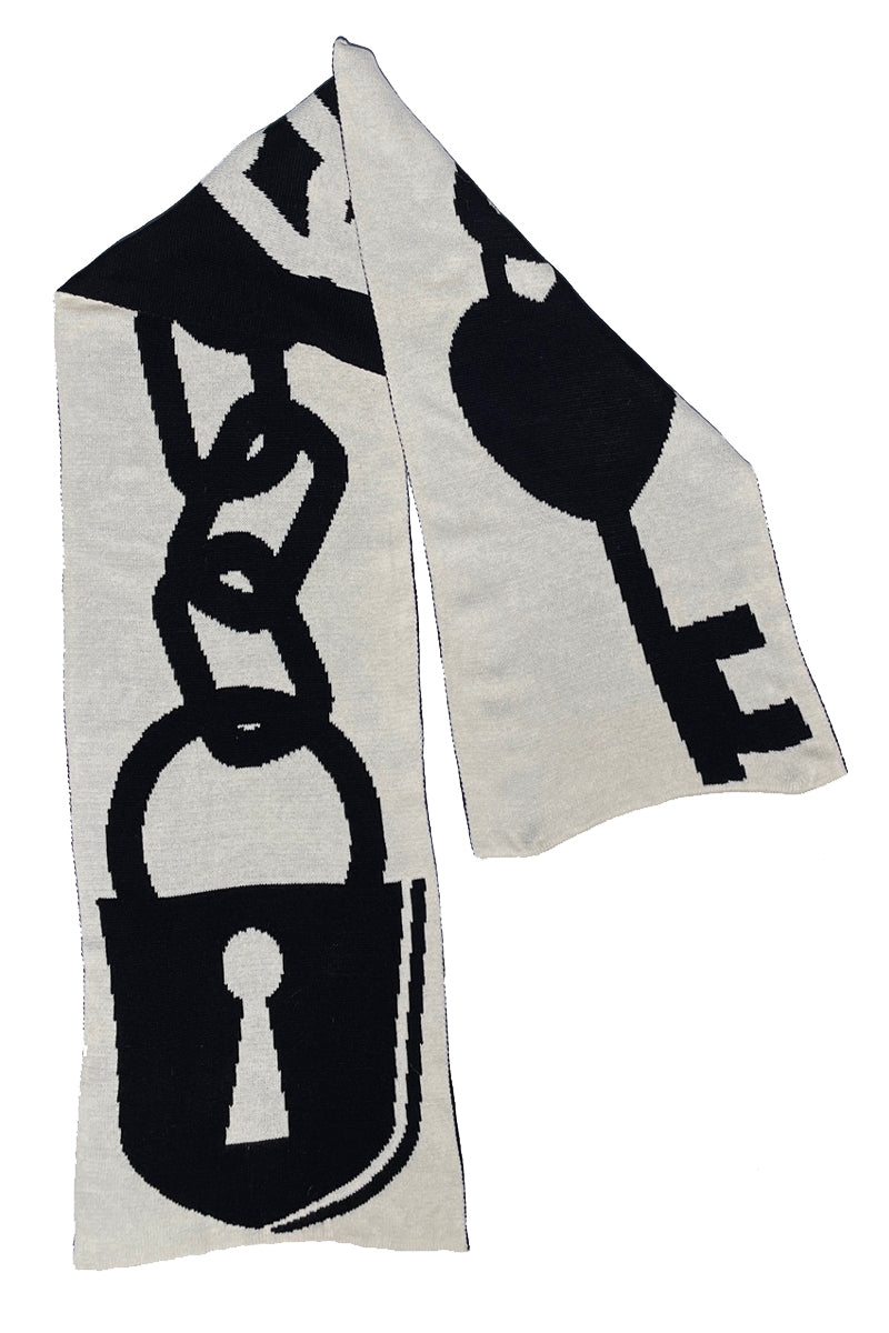 double layered intarsia knit scarf with a novelty knit-in black and white design of a lock and heart-shaped key connected to each other with a linked chain. Shown folded with black on white side facing out 