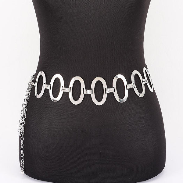 A silver metal chain belt with large flat oval links and a dangling chain extender, shown from the front on a black mannequin torso against a white background.