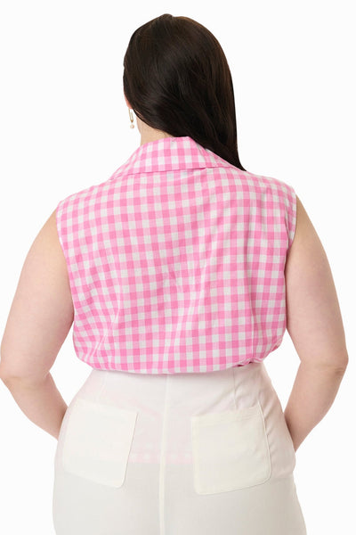 Plus size model wearing sleeveless cotton button-up blouse in white and pink gingham pattern with pointed notched collar. Shown tucked into pants from back