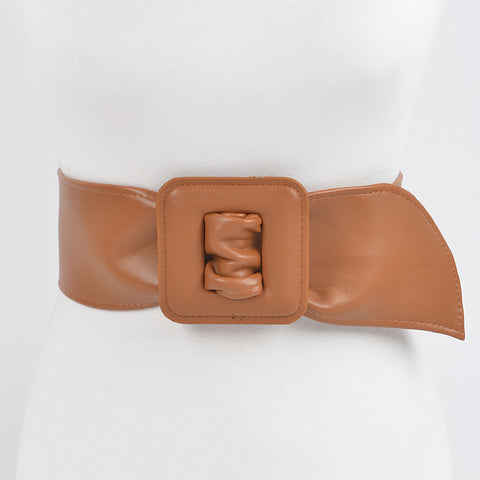 Light brown matte finish faux leather belt with a large square self buckle on dress form on a white background