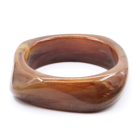 shiny 7/8" wide irregular square-shaped semi-transparent resin bangle with rounded edges in a milky marbled shade of amber