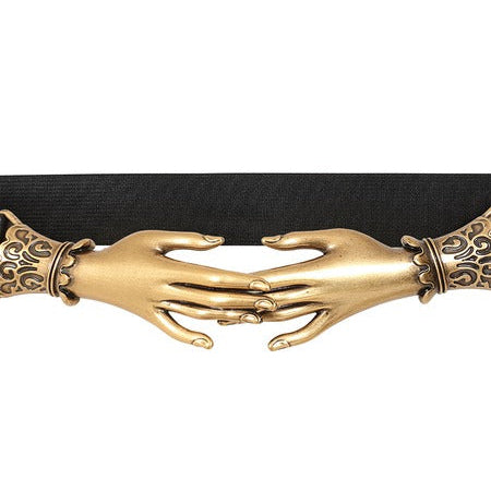 A black elastic wait belt featuring a large gold-toned metal buckle shaped like two hands clasped together, with ornate decorative details on either side, shown in close up against a plain white background.