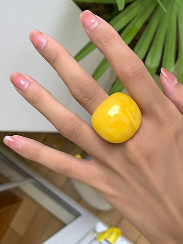 Rounded acrylic cocktail ring in bright yellow. Worn by model